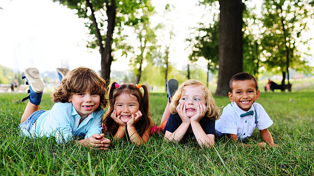 friends of preschool kids playing lying on the grass in the Park on a summer day