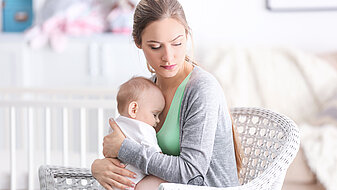 Depressieve moeder met baby die thuis in een stoel zitten